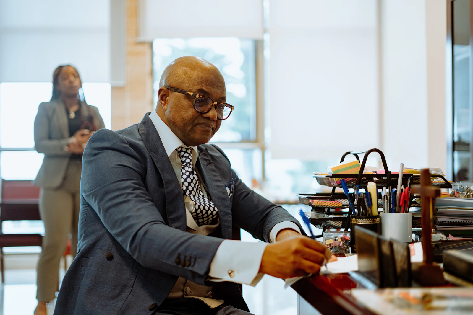 An attorney reviewing a document at a desk while a colleague looks on.