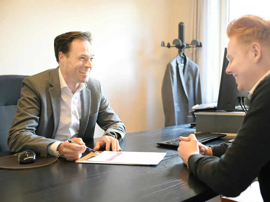 Two attorneys in suits reviewing a case file together across a table.