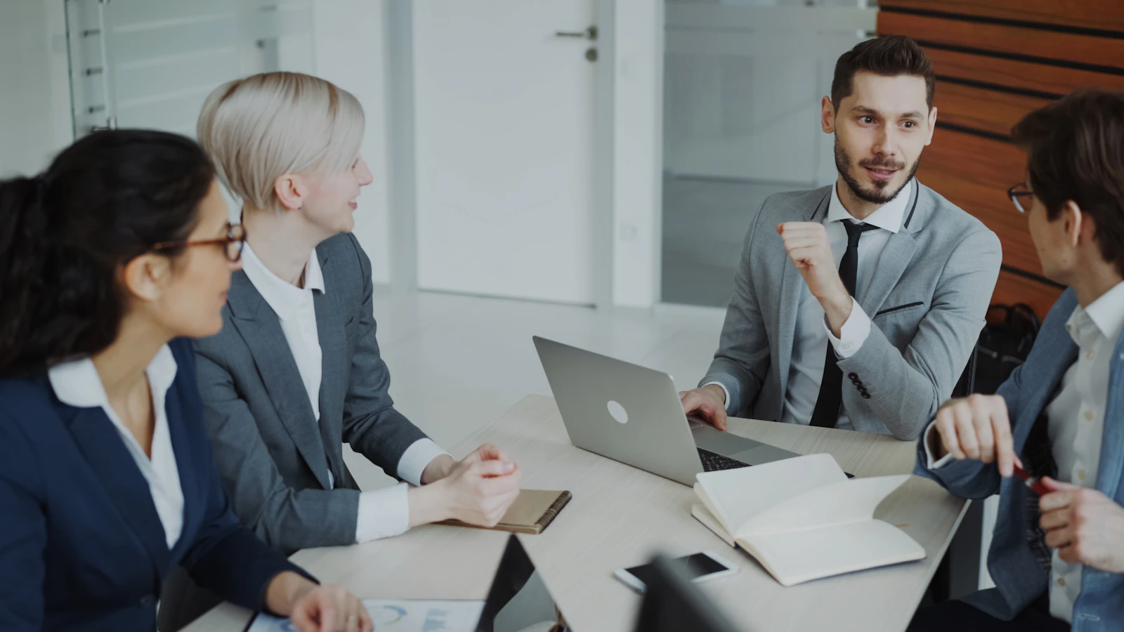 Four professionals reviewing documents together around a table in a bright office.